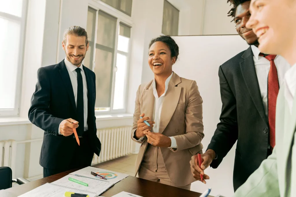 Team members standing around a table, engaged in a cheerful discussion.