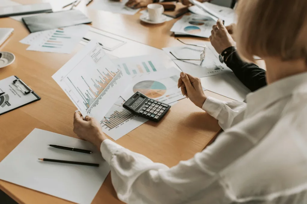 Hands of an executive analyzing financial data with charts on a desk.