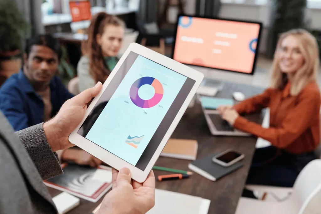 Tablet showing pie chart in a business meeting with colleagues.