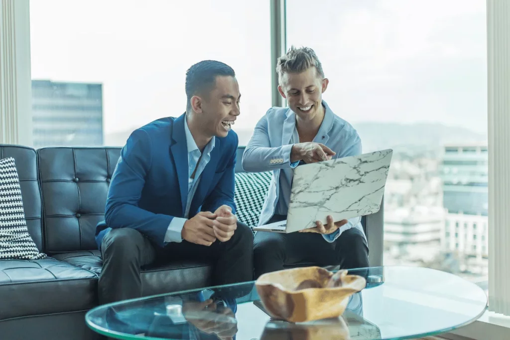 Two businessmen in suits discussing work on a laptop.