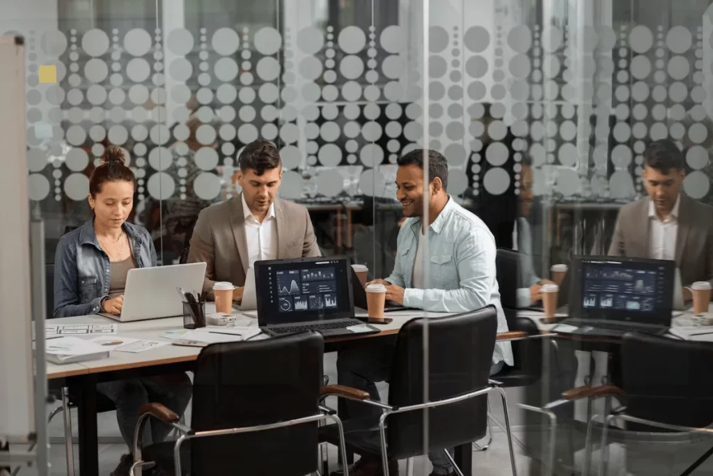 Group of professionals analyzing data on computers.