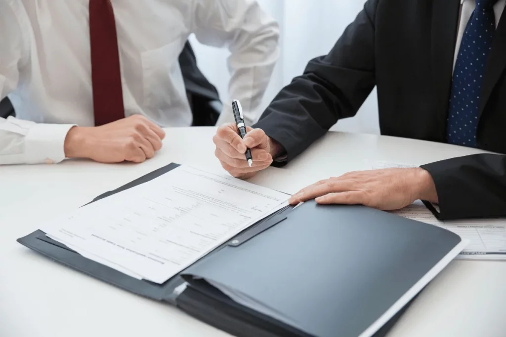 Two men in business attire reviewing documents at a desk.