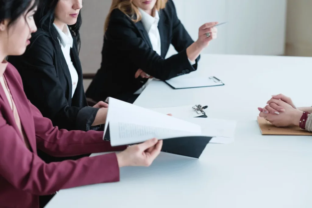 Women in a business meeting, one reviewing papers while others listen attentively.