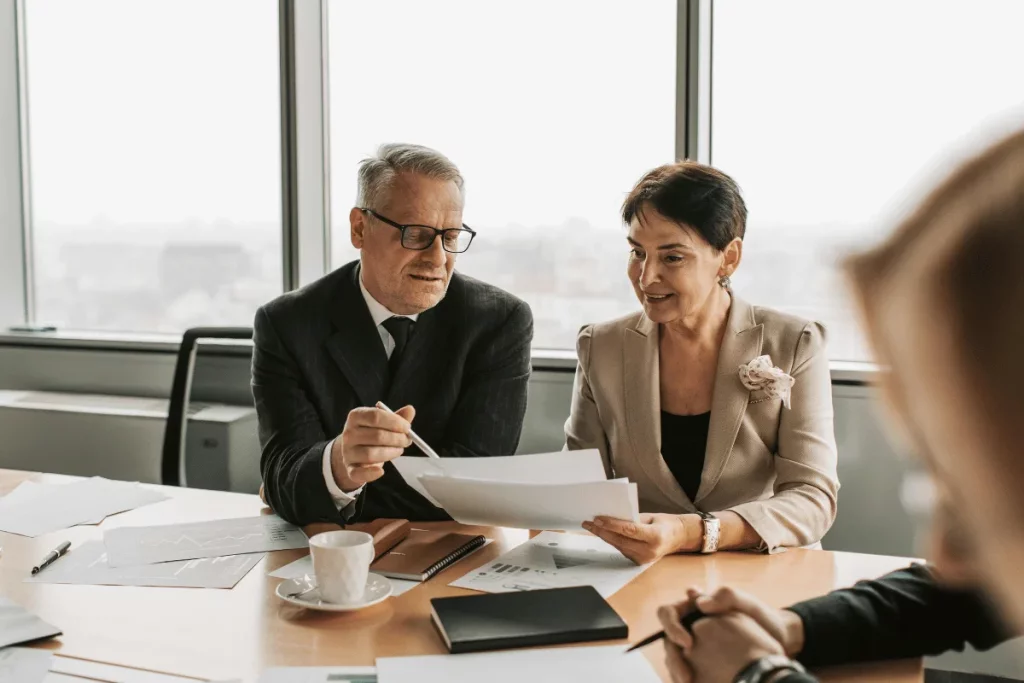 Two senior managers analyzing reports at a business meeting.