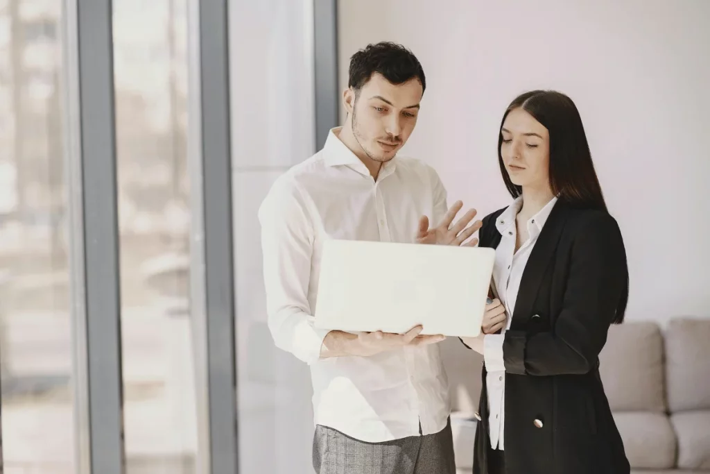 Business colleagues discussing work on a laptop in a bright office.