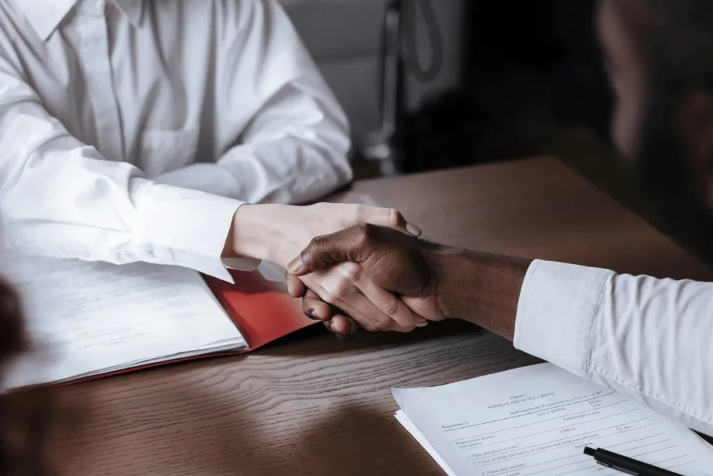 Focused image of a handshake in an office setting, documents on the table.