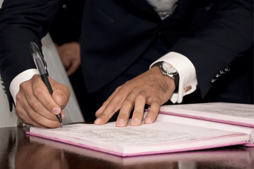 Business professional signing a document at a formal event.