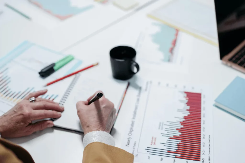 The individual is taking detailed notes in a notebook while analyzing data.