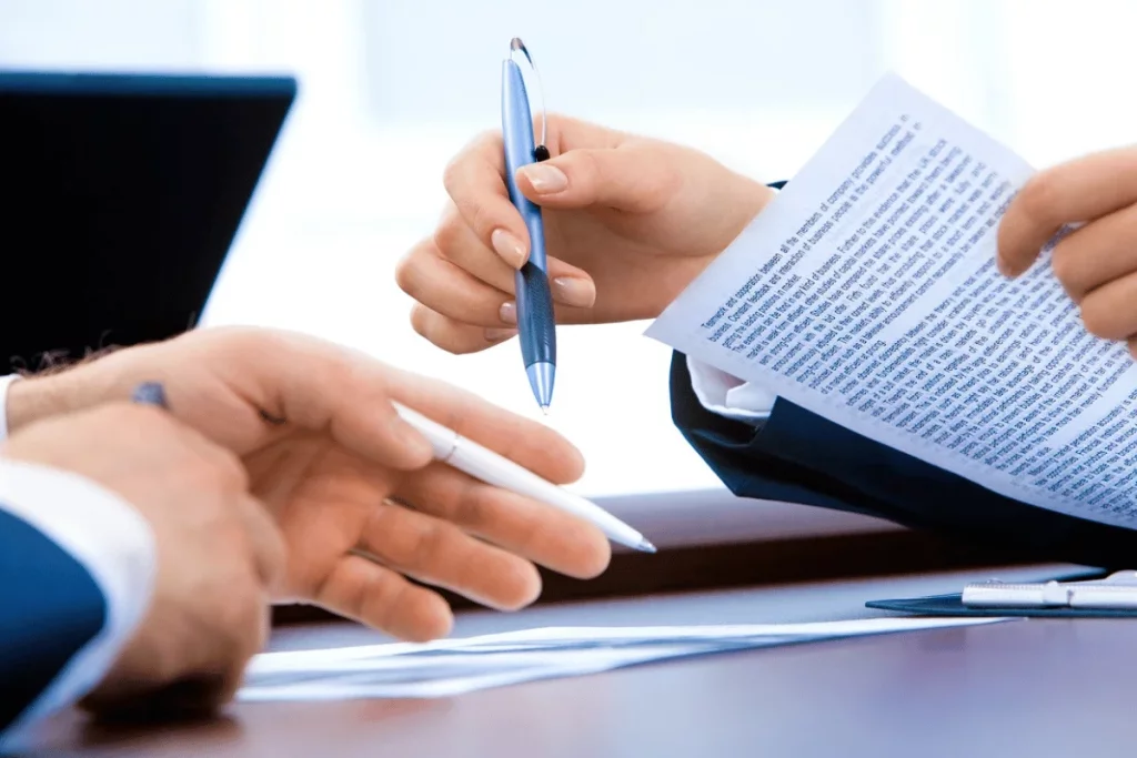 Two people in a business setting, exchanging a paper document.