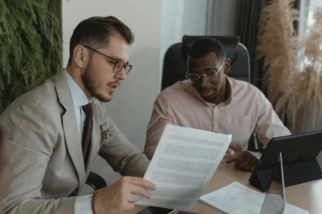Two businessmen reviewing a document together in an office setting.