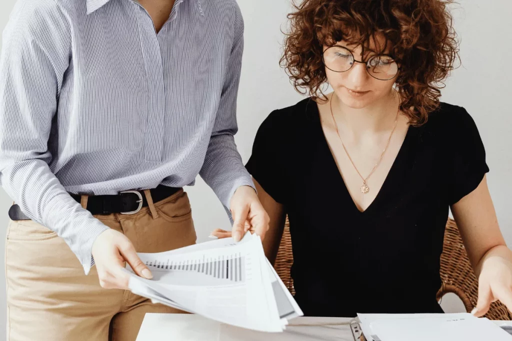 Close-up of two colleagues organizing papers during a meeting.