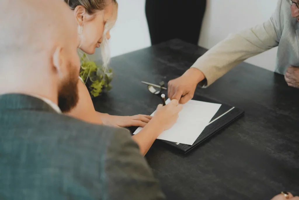 Close-up of a business meeting where a person signs an official document.