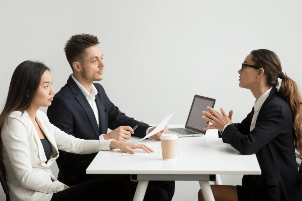 Three people sitting at a table talking to each other.