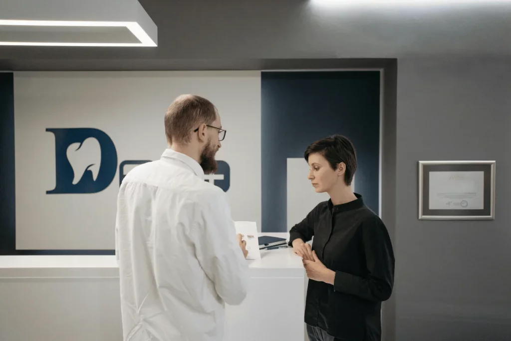 A dentist and a woman talking at a dental clinic reception.