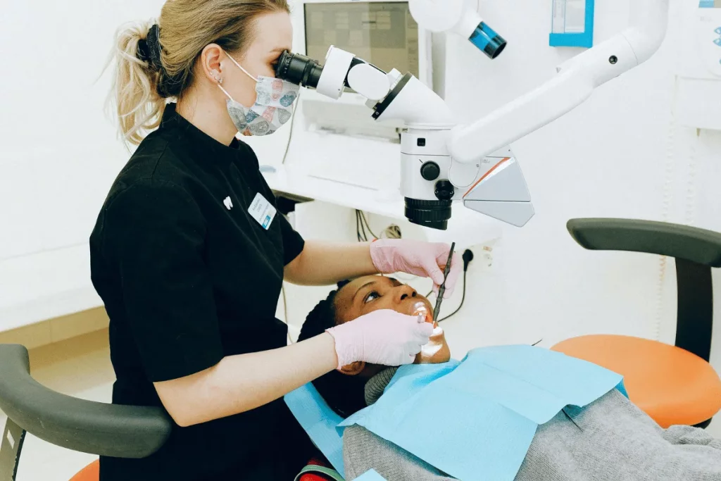 A dentist uses a microscope to examine a patient's teeth during a dental procedure.