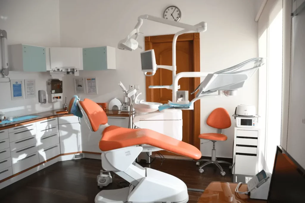 A dentist’s office featuring a well-equipped treatment chair, a computer monitor, and various dental tools.