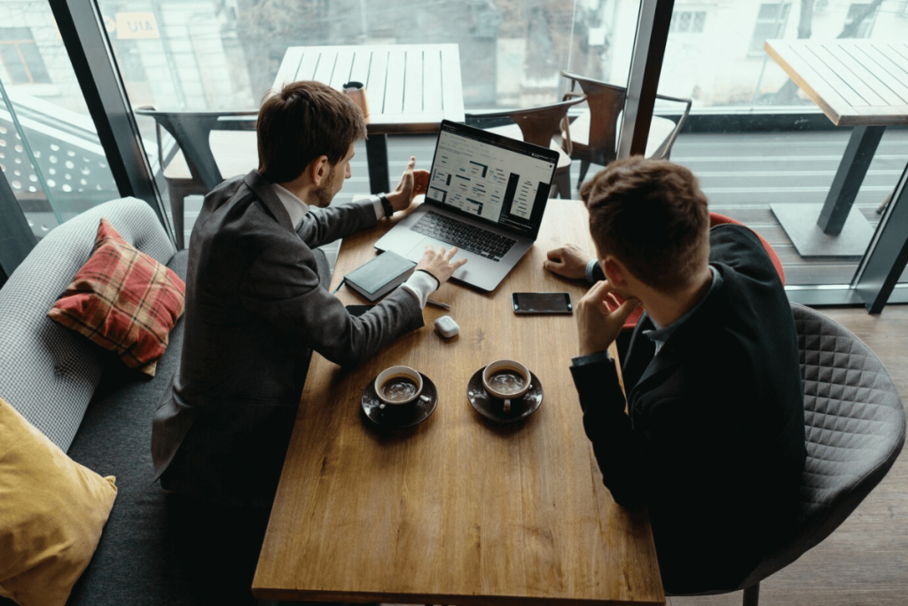 Two individuals sitting at a table looking at a laptop.