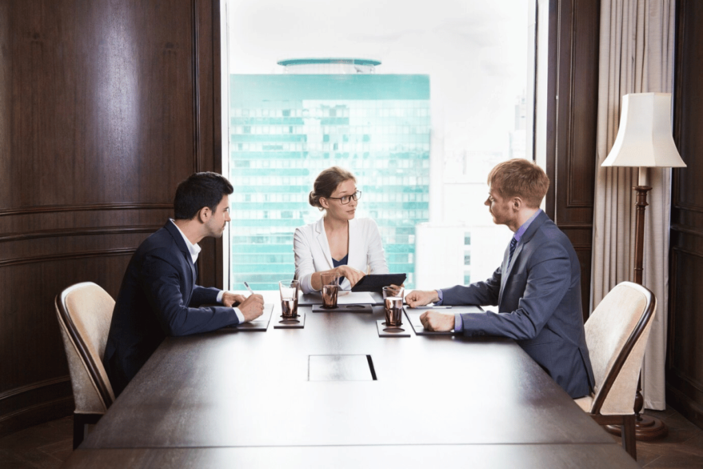 Three people sitting at a conference table.