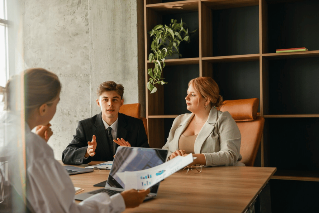 Three people sitting at a table in an office.