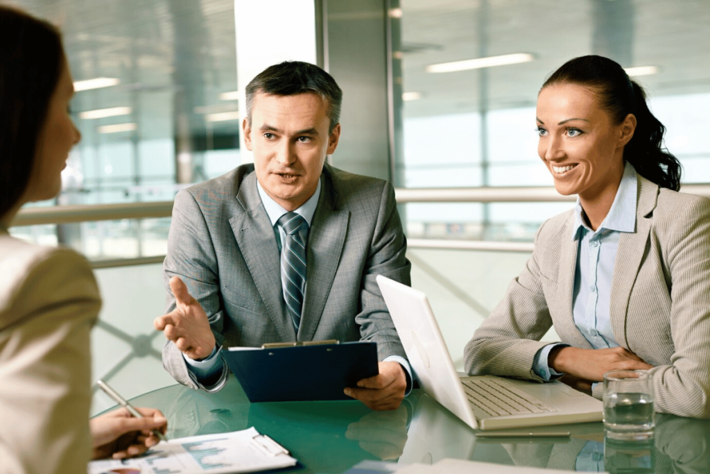 Three people sitting at a table with a laptop.