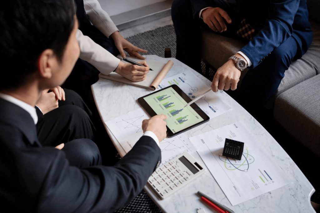 A group of people sitting around a table with a tablet.