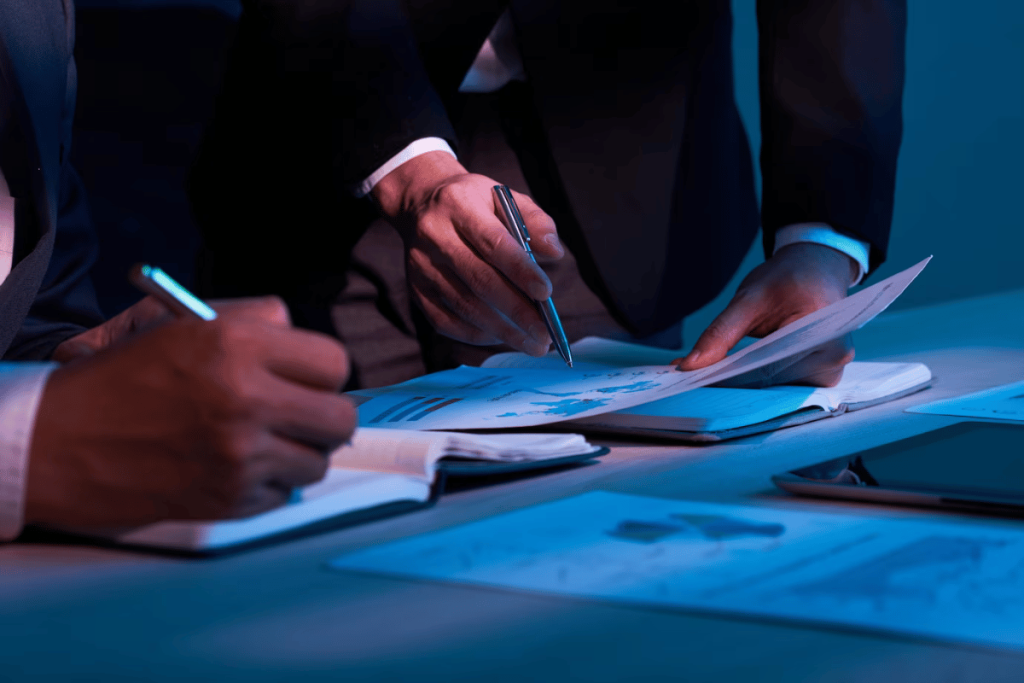 Business people working at a desk with a laptop and papers.