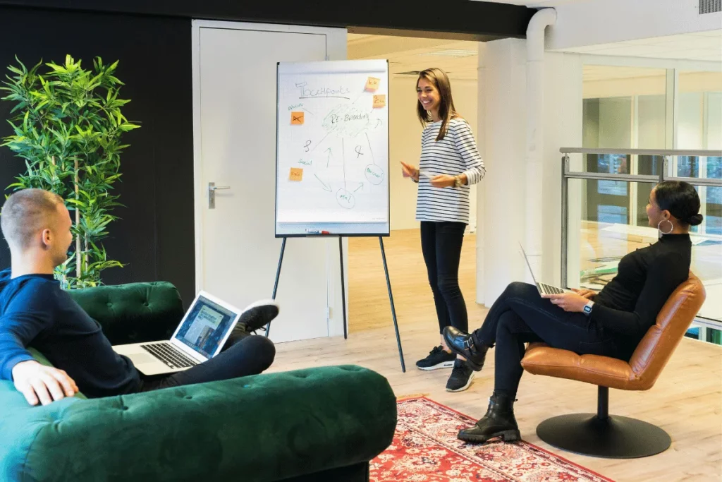 Team members in a casual office setting discussing strategies on a flip chart.