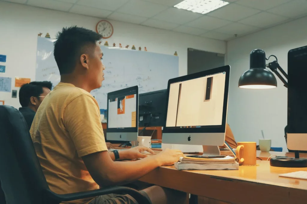 A focused programmer working on a desktop computer in a well-lit office.