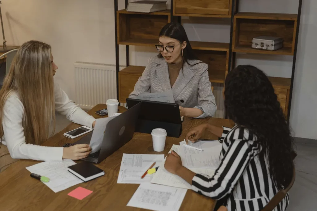Group of female colleagues working together with digital and paper resources.