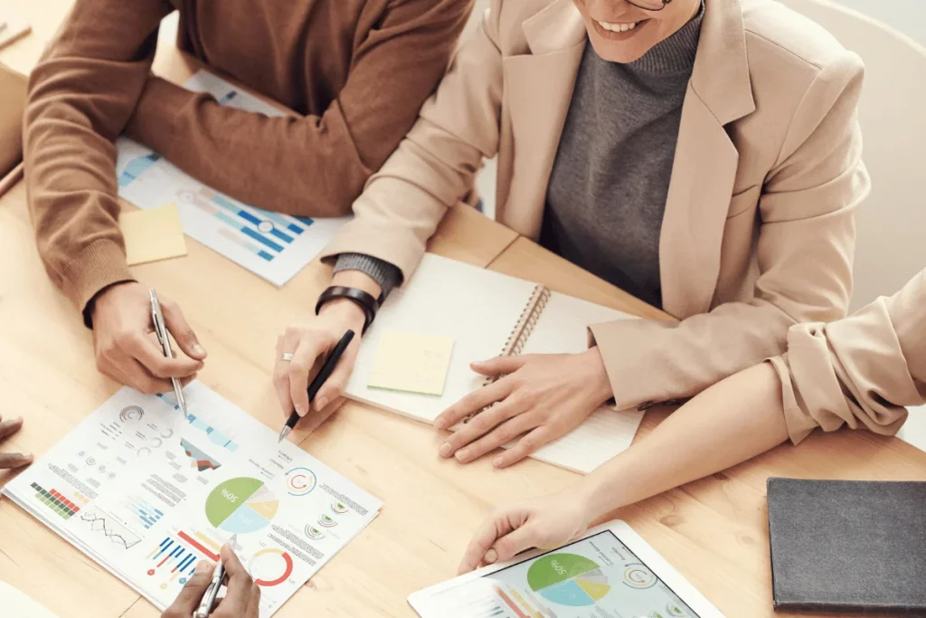 Two professionals collaborating over graphs and charts during a business meeting.