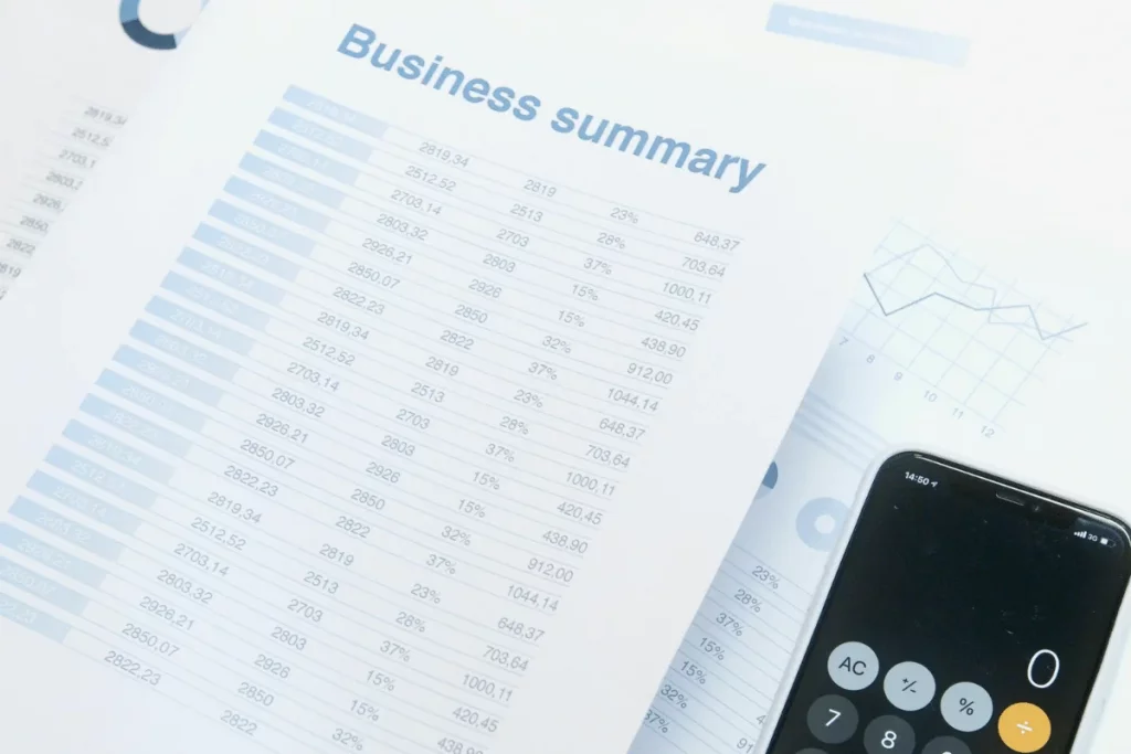 Business summary document with financial data and smartphone calculator.