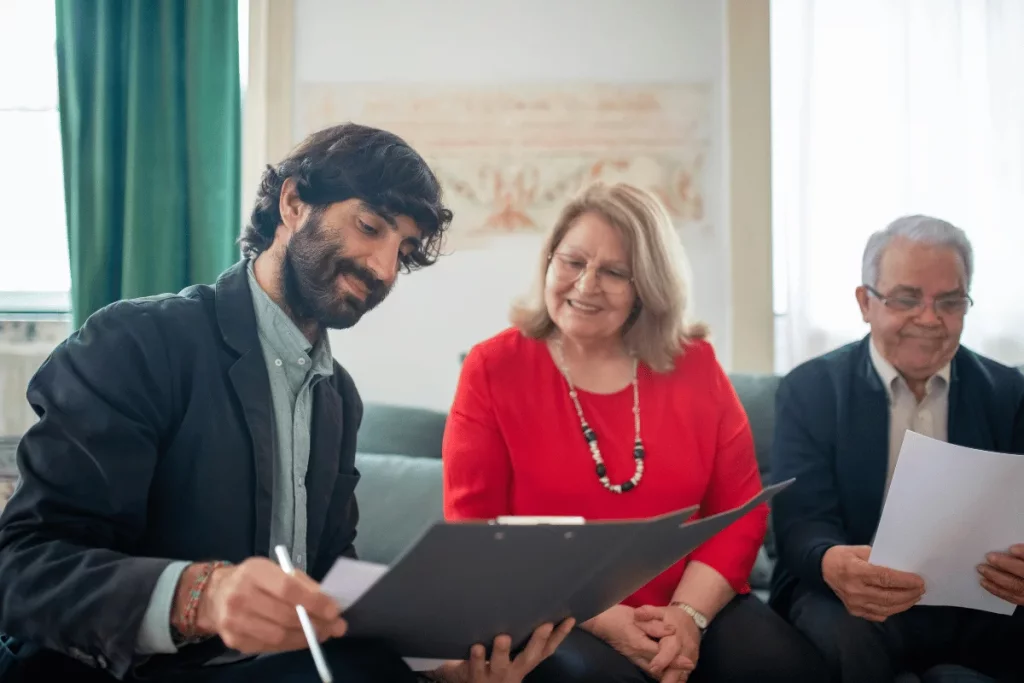 Professional meeting with a younger man explaining paperwork to two senior individuals.
