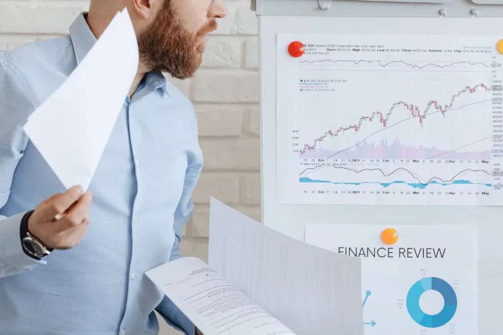 Businessman reviewing detailed stock market analysis on wall chart.