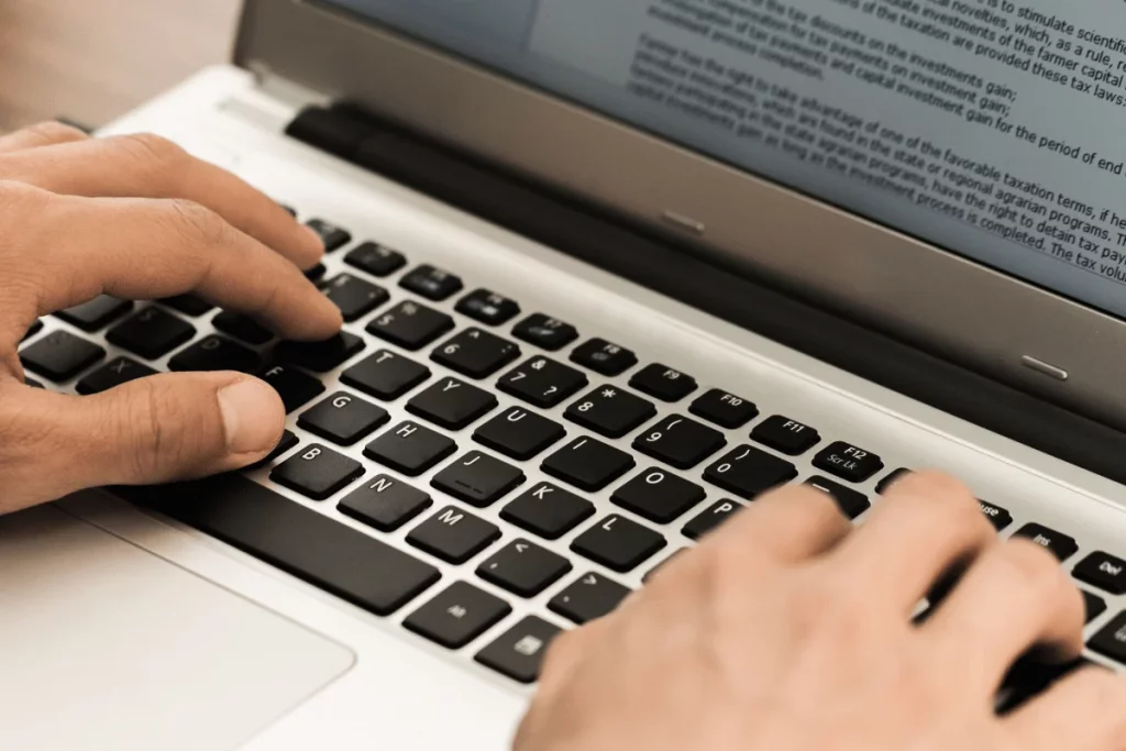 Close-up of fingers on a laptop keyboard, engaged in typing.
