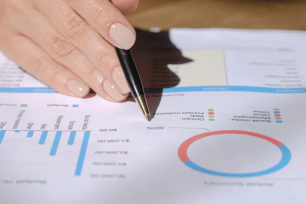 Focused view on a business report with hand pointing at statistical data with a pen.