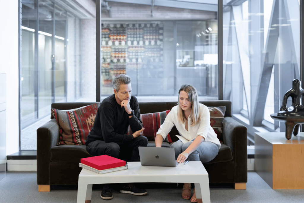Two people sitting on a couch looking at a laptop.