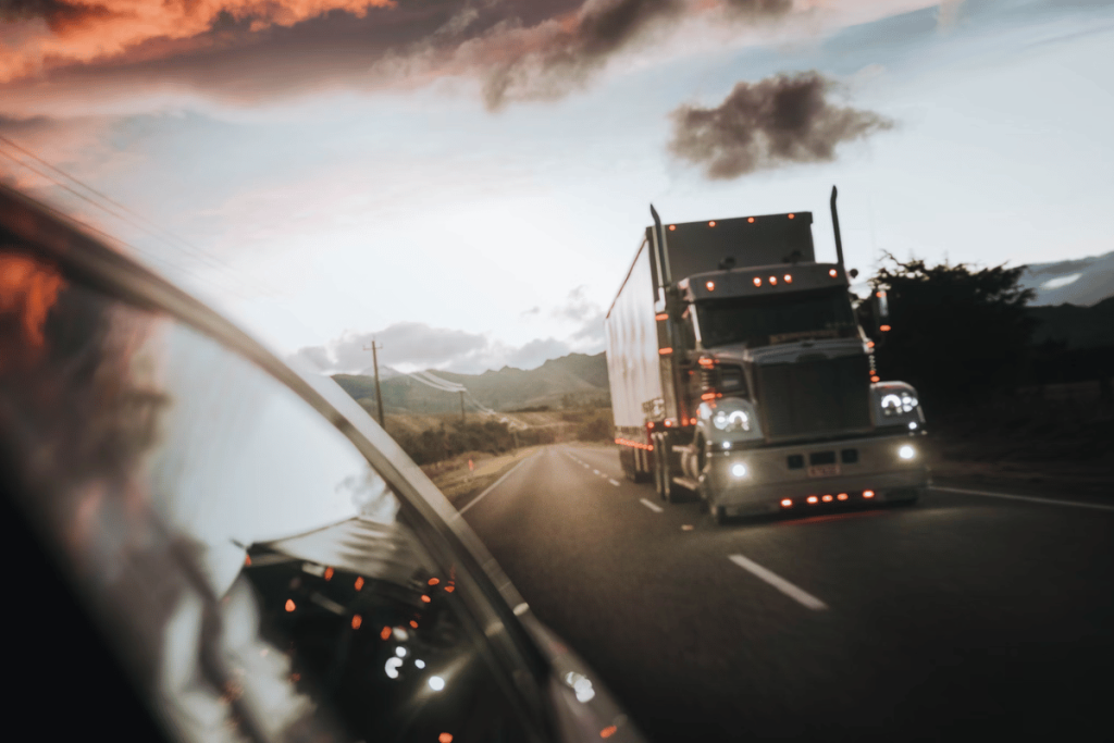 Sunset road trip with a semi-truck captured from a car's side mirror.