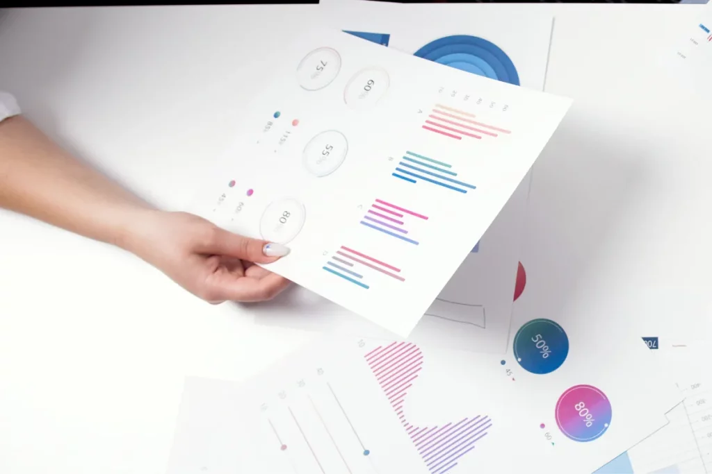 Close-up of a hand holding colorful data charts and graphs, with a focus on the graphical information.