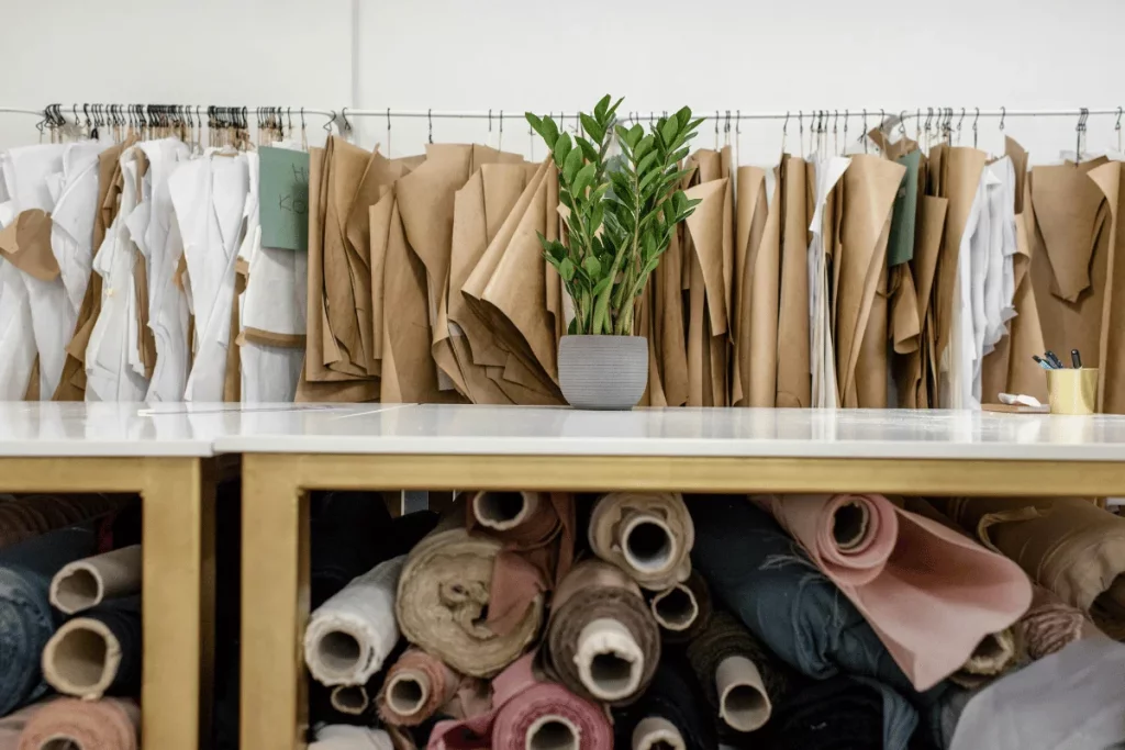 Fashion design studio with patterns on hangers and fabric rolls underneath.