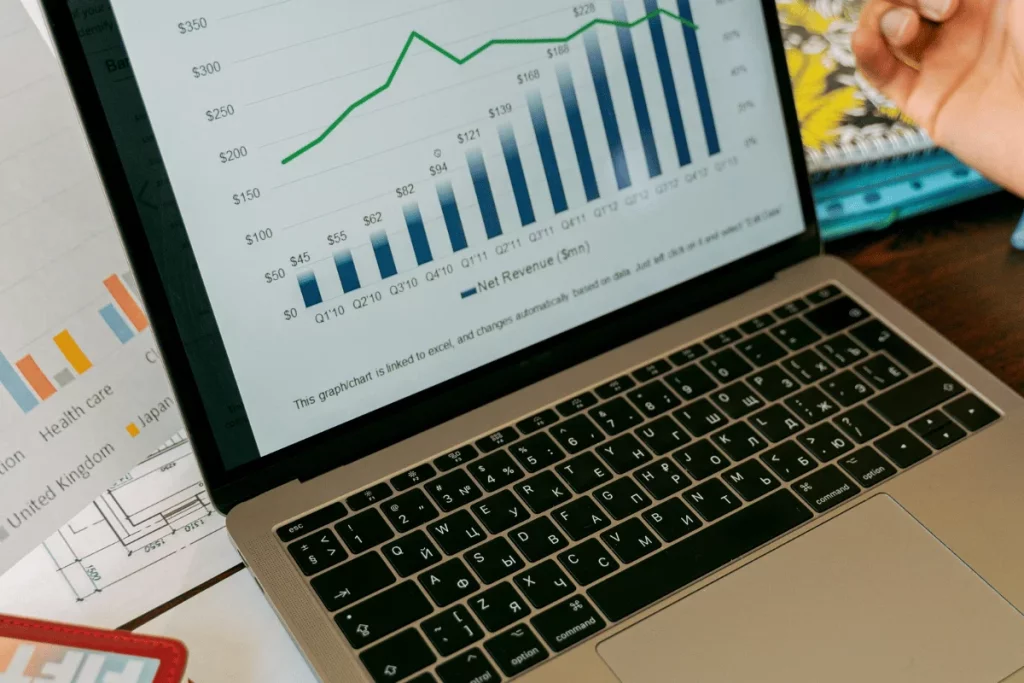 Laptop displaying a bar graph with rising net revenue trends and a line chart.