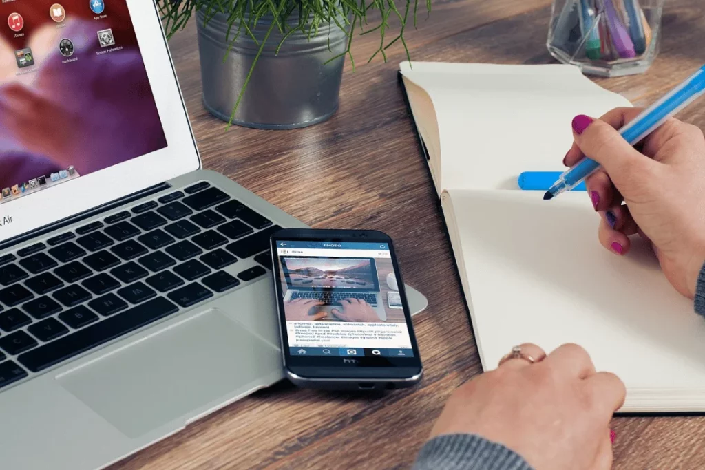 Creative workspace with a MacBook Air, smartphone, and open notebook.
