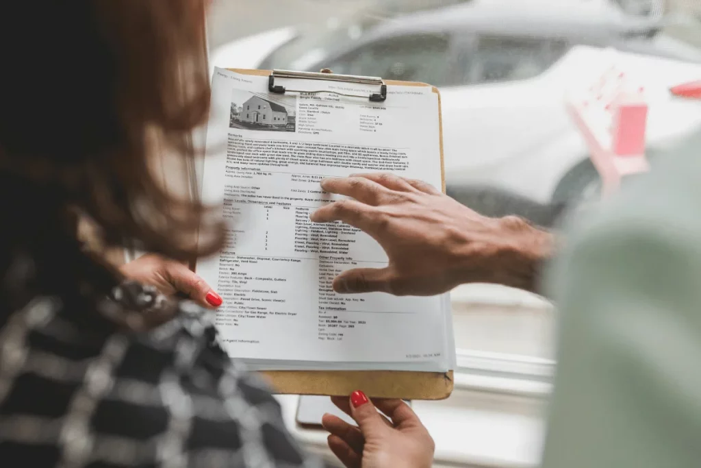 Professionals discussing house features listed on a clipboard.
