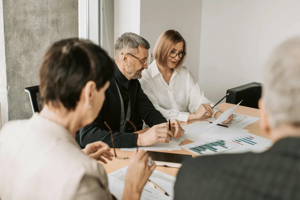 Group of four professionals reviewing documents at a meeting table.
