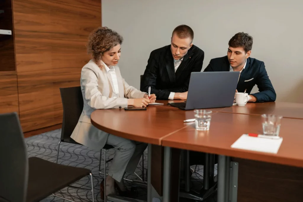 Colleagues in a brainstorming session with a laptop in a corporate setting.