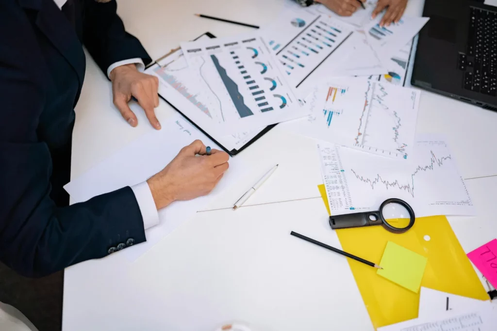 Business professionals analyzing graphs and charts on a white table.