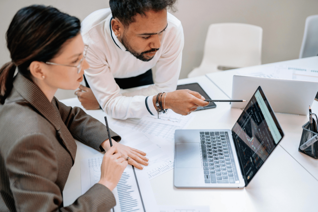 Business professionals discussing over financial documents with a laptop on table.