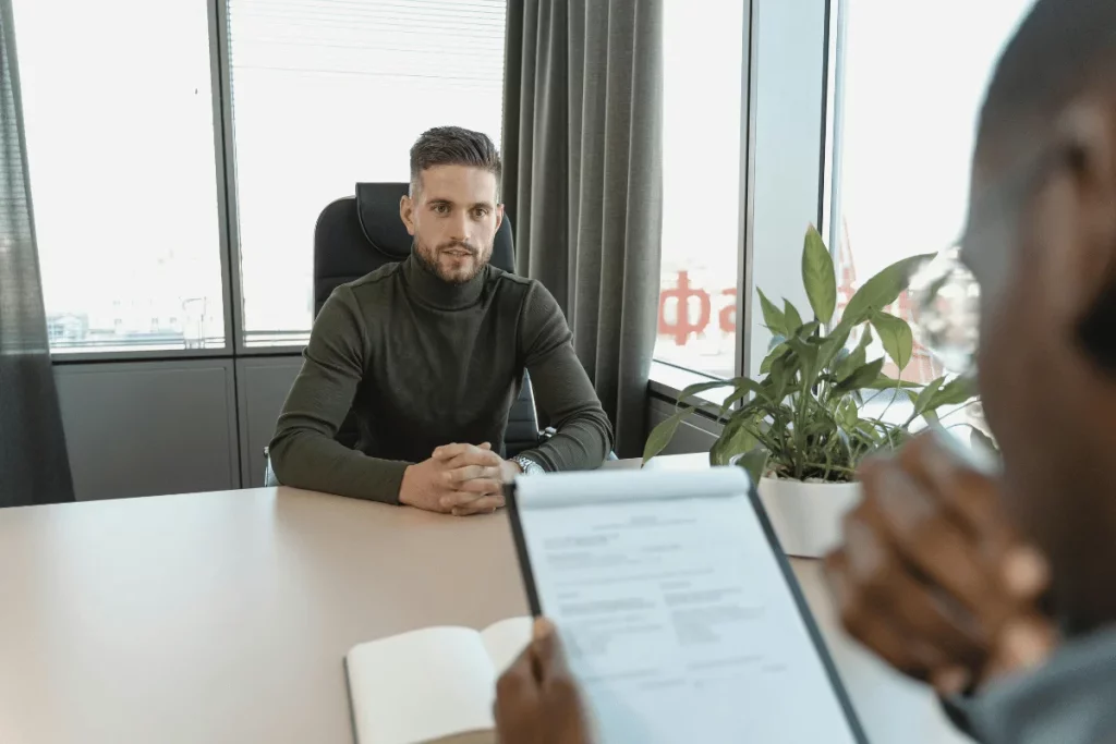 Man in a green sweater having a discussion in an office interview.