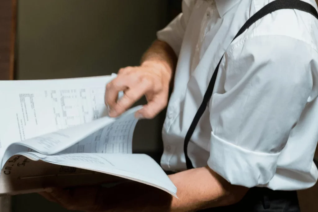 A close-up of a hand turning the pages of a ledger or accounting book, revealing printed data.