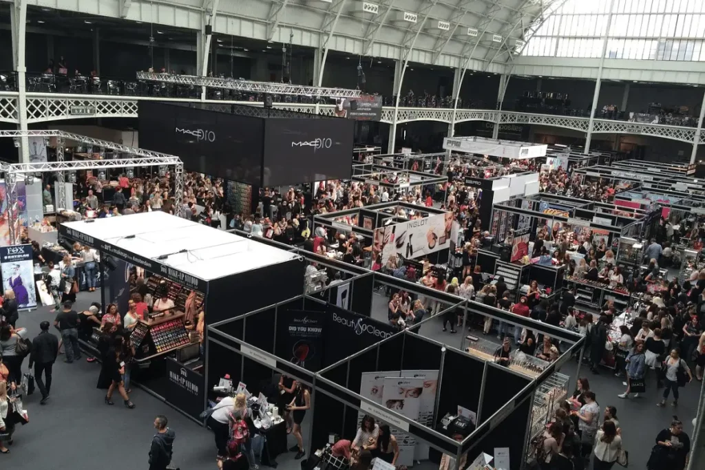 Large indoor trade show with multiple booths and a crowd of attendees.