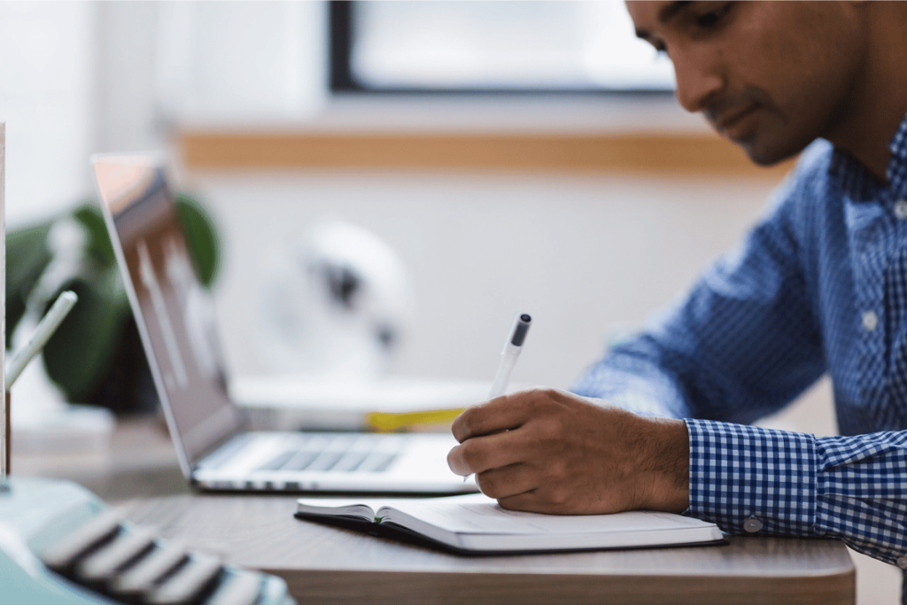 A person sitting at a desk with a notebook and pen.
